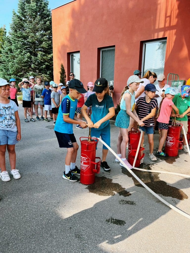 Feuerwehr Zettling beim Schulsportfest der Volksschule Premstätten 2025 – Kübelspritzen-Station mit Erinnerungsbuttons und Jugendfolder für die Kinder