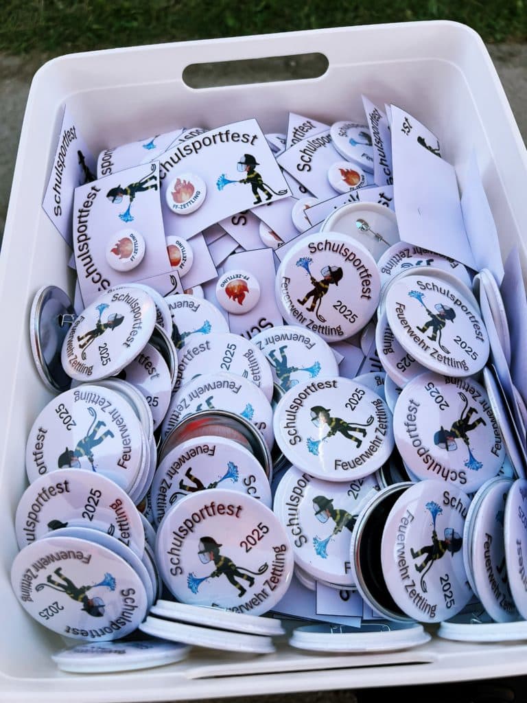 Feuerwehr Zettling beim Schulsportfest der Volksschule Premstätten 2025 – Kübelspritzen-Station mit Erinnerungsbuttons und Jugendfolder für die Kinder