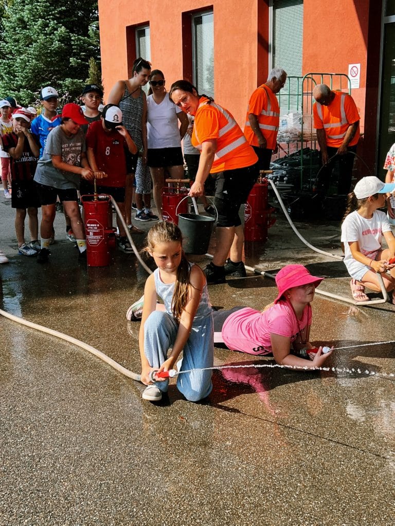 Feuerwehr Zettling beim Schulsportfest der Volksschule Premstätten 2025 – Kübelspritzen-Station mit Erinnerungsbuttons und Jugendfolder für die Kinder